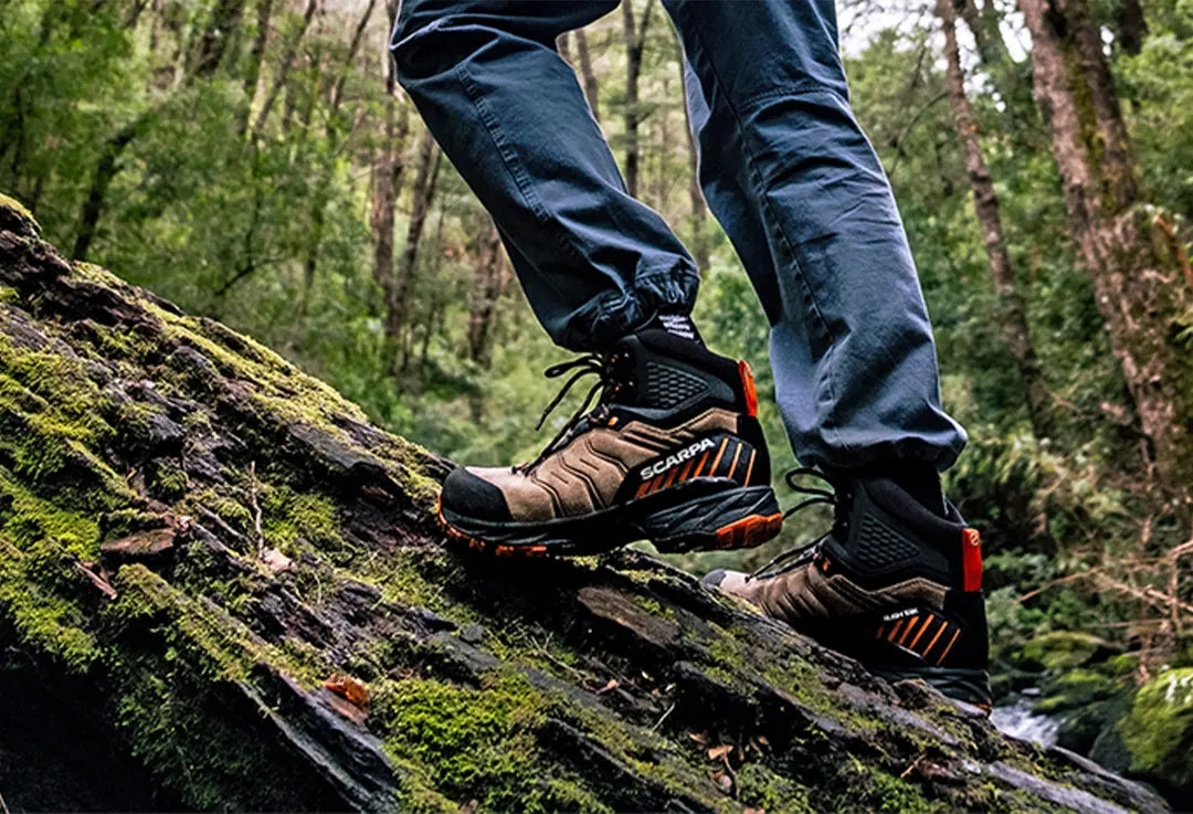 uomo che cammina nel bosco con scarponi da montagna