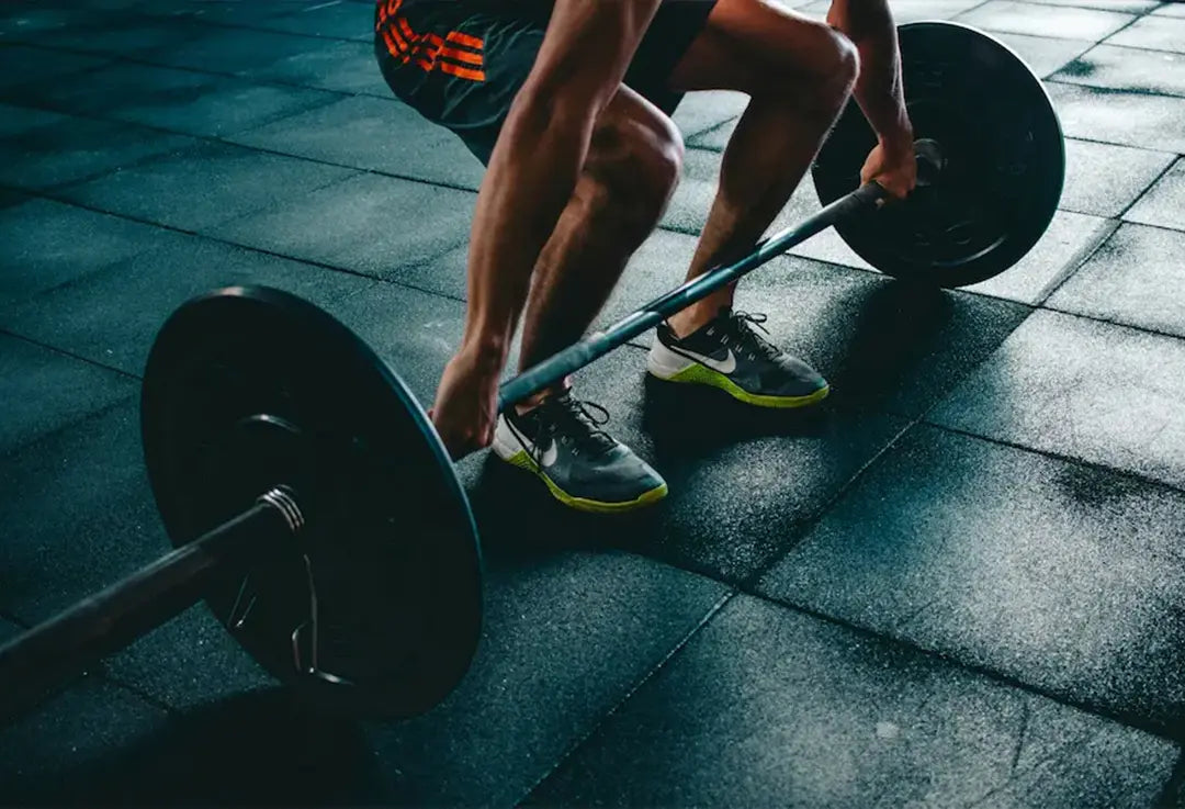uomo in palestra che solleva pesi con addosso le scarpe a palestra