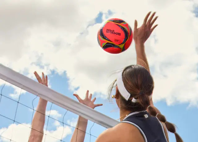 Primo pino di una ragazza che sta per attaccare un pallone da beach volley