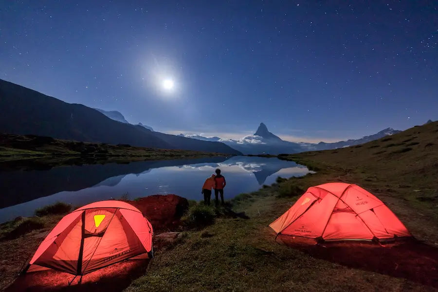 due tende in primo piano con paesaggio di montagna di sera come sfondo